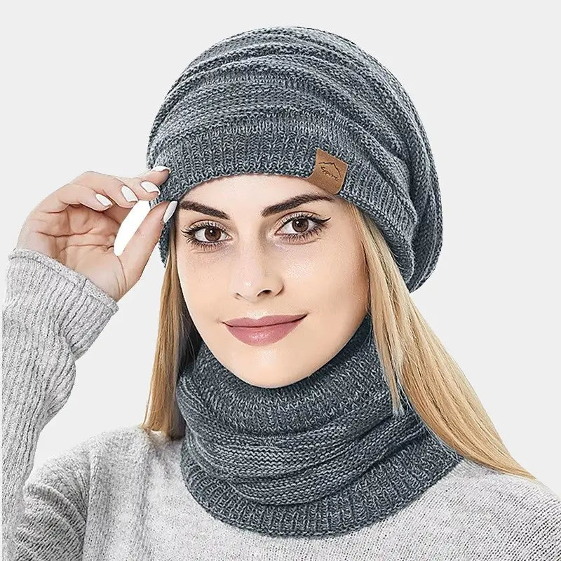 Femme ajustant un bonnet cagoule 2 en 1 gris clair en tricot, couvrant la tête et le cou, parfait pour les journées froides.