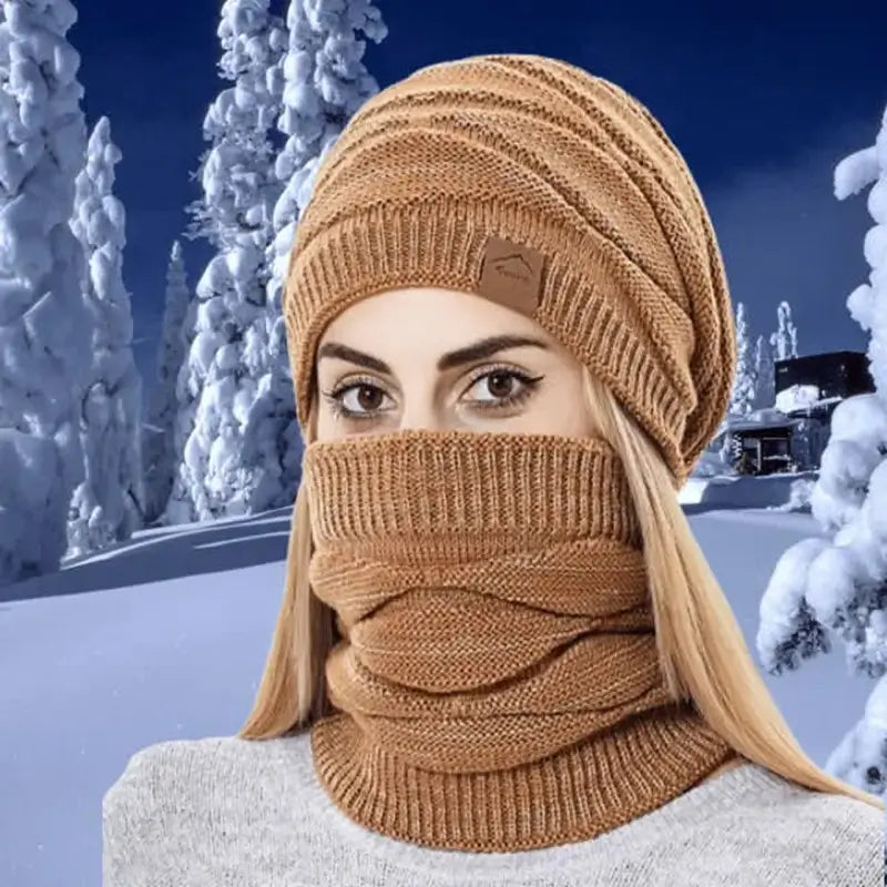 Femme portant un bonnet cagoule 2 en 1 coffee en tricot épais, couvrant entièrement le visage, idéale pour l'hiver en extérieur avec un décor enneigé en arrière-plan.