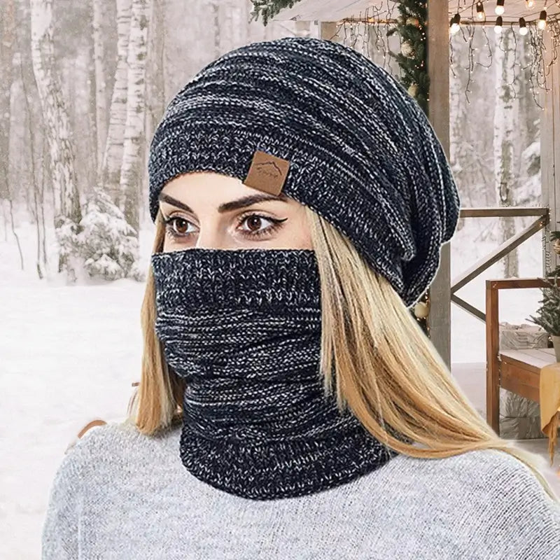 Femme avec un bonnet cagoule 2 en 1 gris anthracite, dans un décor hivernal de forêt enneigée, parfait pour les activités en extérieur.