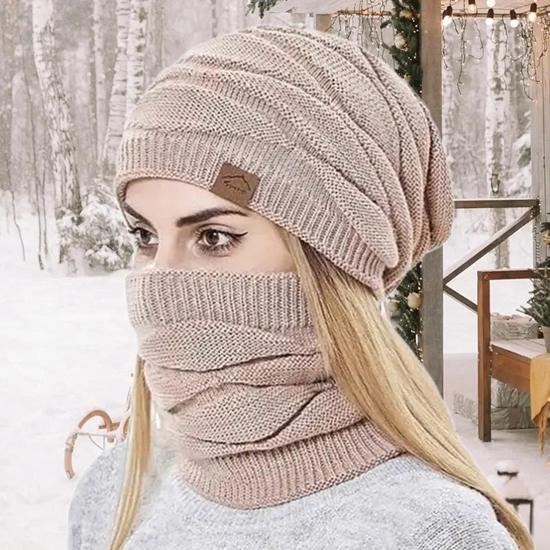 Femme avec un bonnet cagoule 2 en 1 rose dans une forêt enneigée, mettant en valeur le confort et la chaleur pour les activités hivernales.