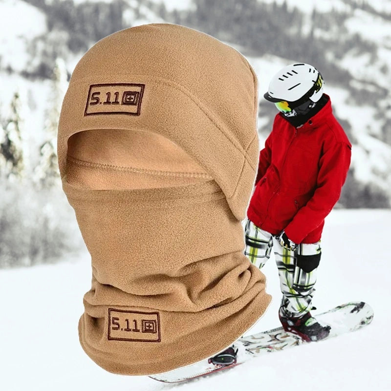 Bonnet cagoule kaki en polaire porté par un skieur dans un paysage enneigé, idéal pour une protection contre le froid lors des activités hivernales comme le ski.