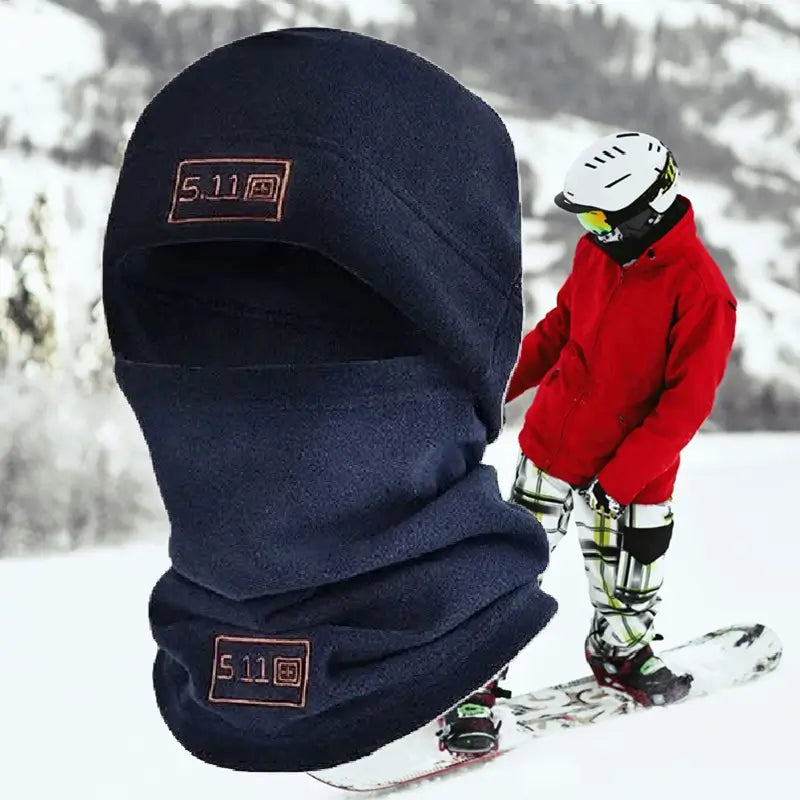 Bonnet cagoule marine en polaire porté par un skieur dans un environnement enneigé, offrant une excellente isolation thermique pour les sports d’hiver.