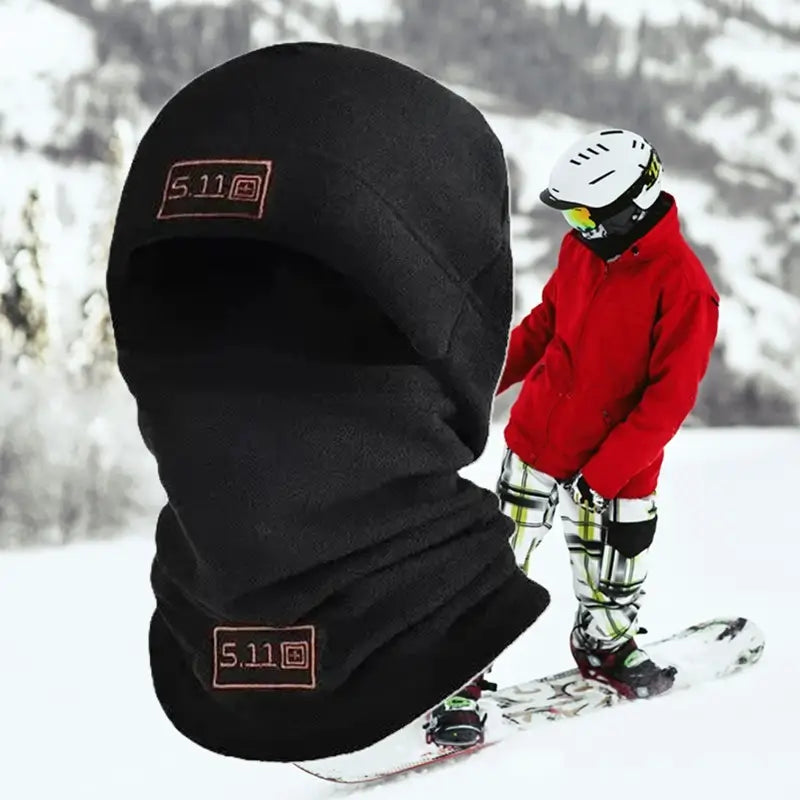 Bonnet cagoule noir en polaire porté par un skieur dans un décor enneigé, offrant chaleur et protection contre le froid, parfait pour les sports d’hiver comme le ski.