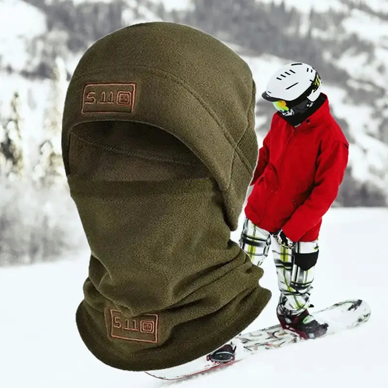 Bonnet cagoule vert en polaire porté par un skieur dans un paysage enneigé, offrant une protection efficace contre le froid et le vent, idéal pour les sports d’hiver.