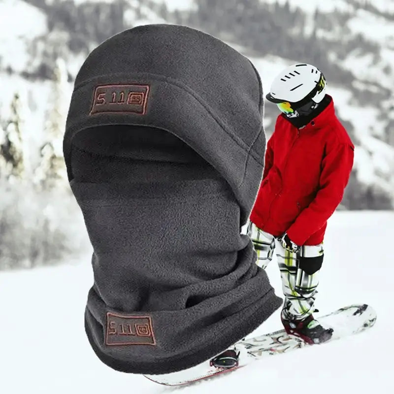 Bonnet cagoule gris en polaire porté par un skieur dans un environnement enneigé, offrant une protection optimale contre le froid et le vent, idéal pour les activités hivernales comme le ski.