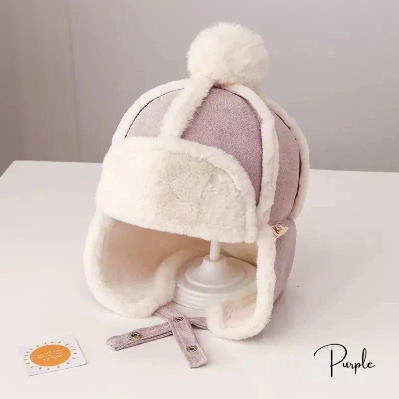 Bonnet Chapka Enfant en tissu violet et blanc, avec coutures apparentes et intérieur en fausse fourrure, posé sur un support blanc avec un fond neutre.