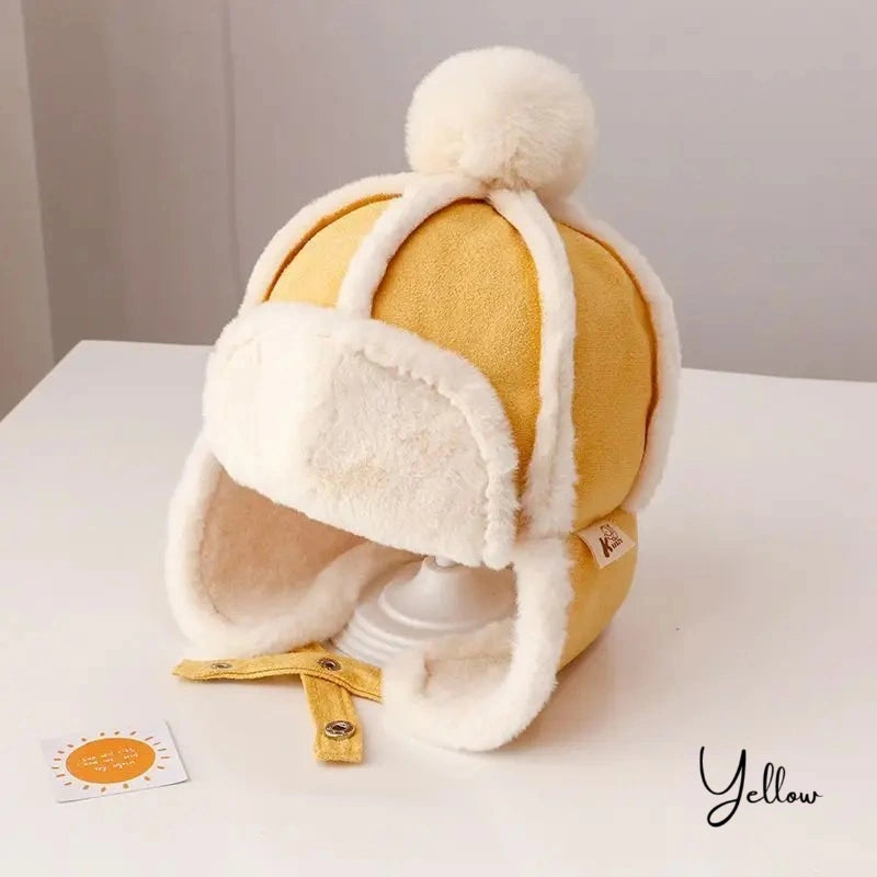 Bonnet Chapka Enfant jaune avec intérieur en fausse fourrure blanche, pompon en laine et attaches ajustables, présenté sur un support blanc avec un fond neutre.