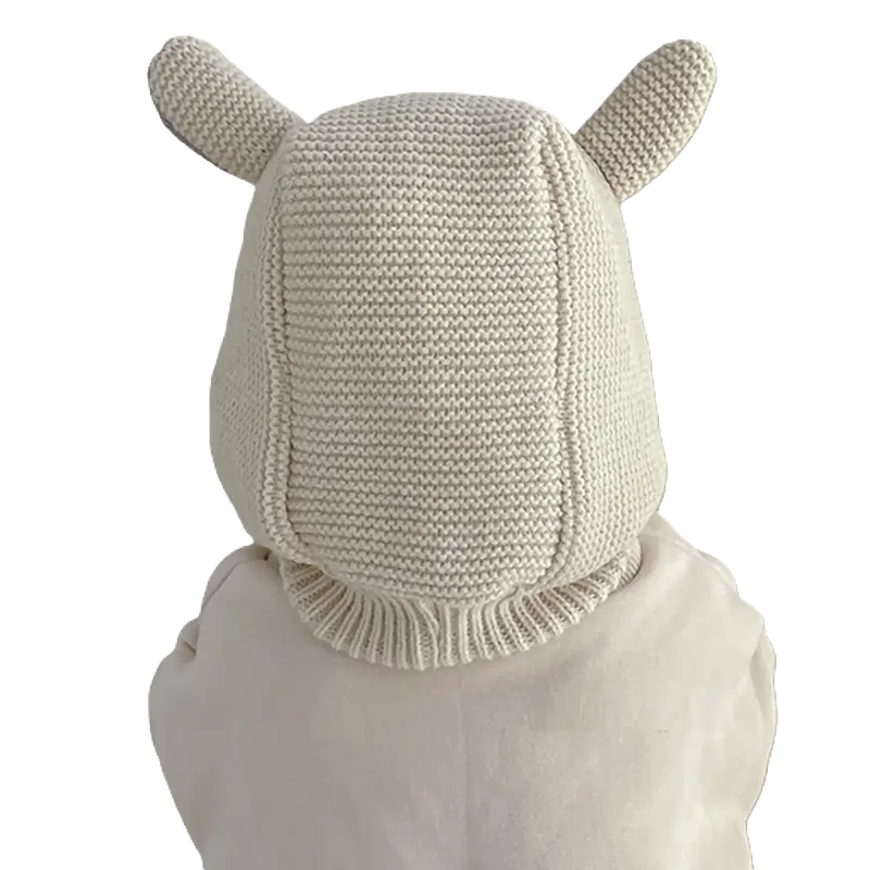 Vue de dos d’un bébé portant une cagoule bébé 6 à 24 mois en tricot blanc avec des oreilles mignonnes. Design intégral couvrant la tête et le cou pour une protection optimale contre le froid.