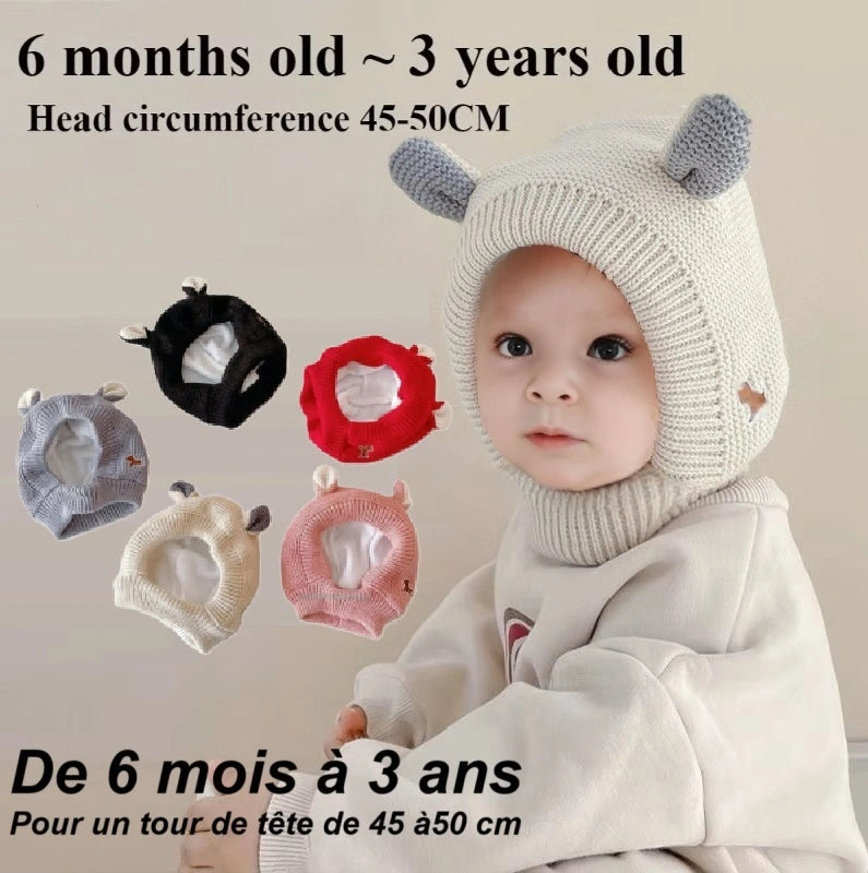 Bébé portant une cagoule bébé 6 à 24 mois en tricot beige avec des oreilles décoratives, sourire doux et regard curieux. Plusieurs variantes de couleurs affichées en bas de l’image. Texte indiquant l'âge recommandé de 6 mois à 3 ans avec un tour de tête de 48 cm.