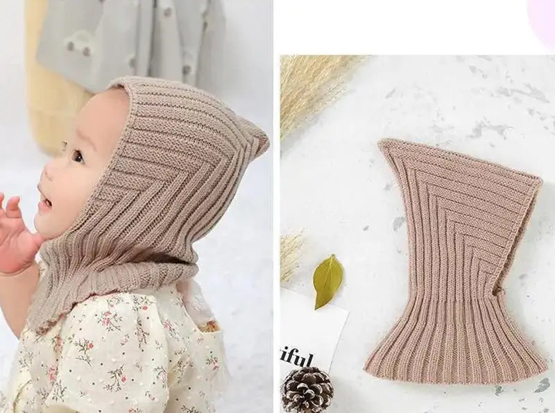 Bébé portant une cagoule kaki en tricot doux, offrant une protection contre le froid, avec un design pratique et ajusté pour les activités extérieures. Cagoule bébé élégante et chaleureuse.