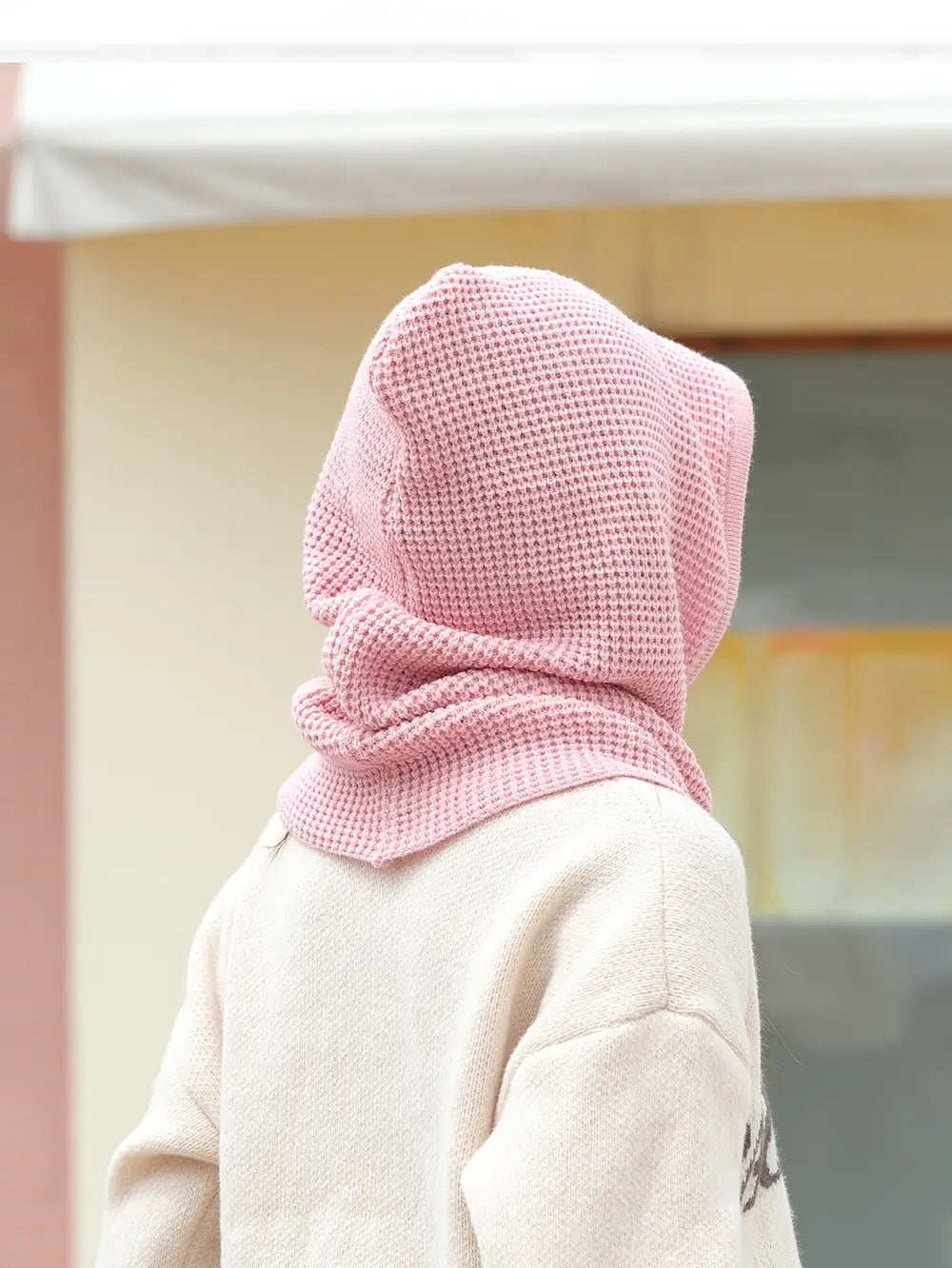 Profil d’une femme avec une cagoule cache cou femme rose, capuche relevée couvrant la tête et le cou, mettant en valeur la texture douce et chaude