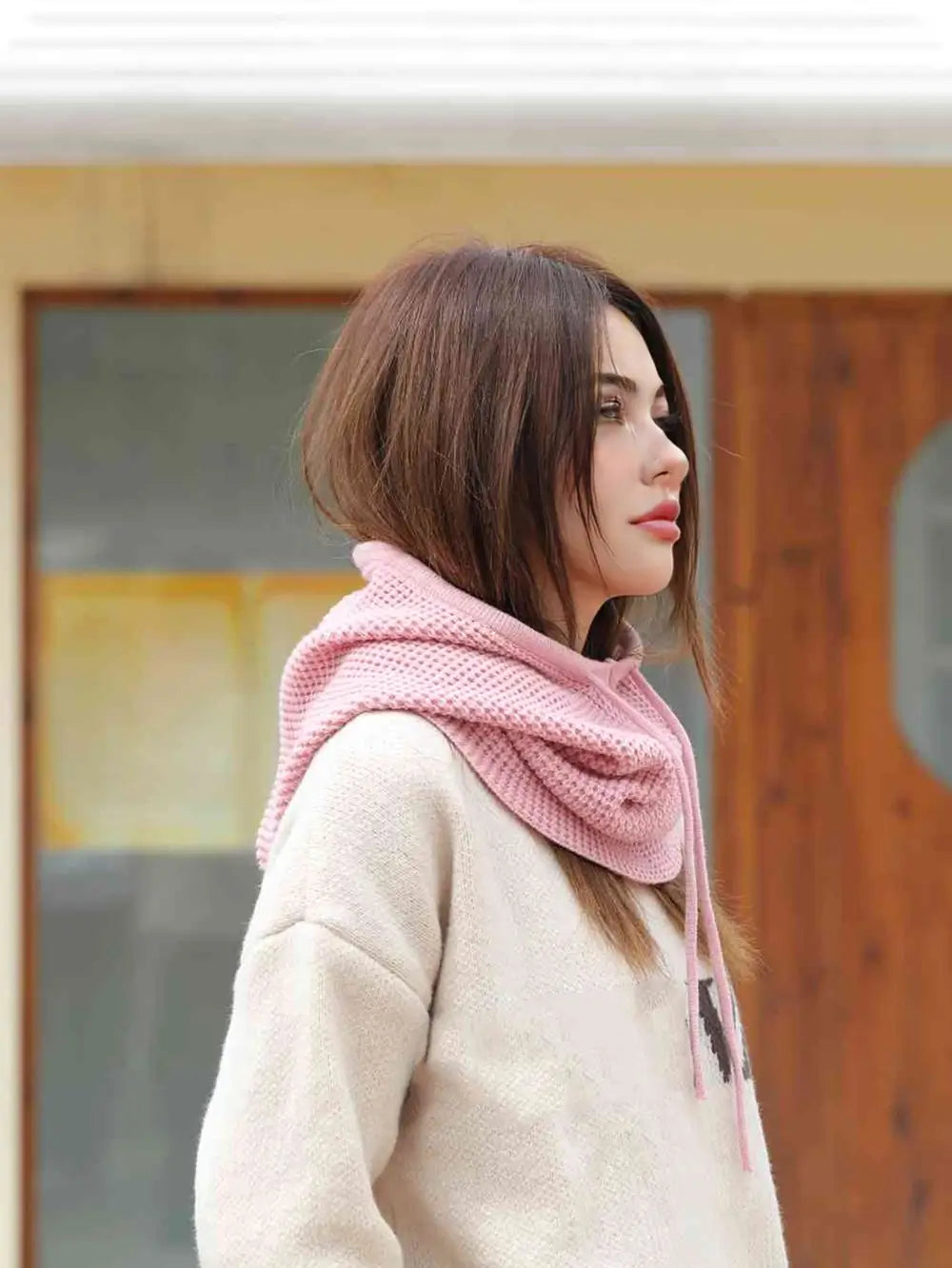 Femme de profil avec une cagoule cache cou femme rose, capuche abaissée reposant sur les épaules, idéale pour un look élégant et confortable.