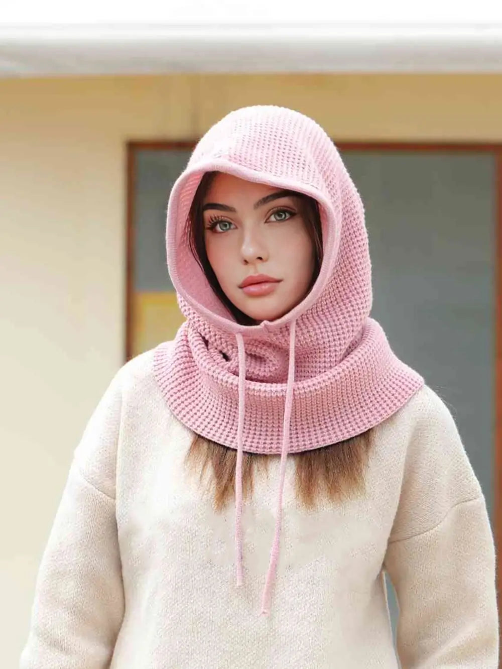 Femme portant une cagoule cache cou femme rose, capuche relevée avec cordons ajustables, idéale pour rester élégante et protégée contre le froid en extérieur.