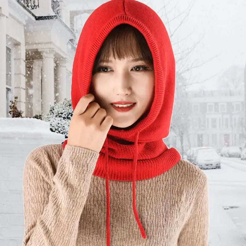 Femme souriante portant une cagoule capuche femme rouge en laine, dans un paysage enneigé. La capuche couvre bien la tête et le cou, offrant chaleur et confort pour l’hiver.