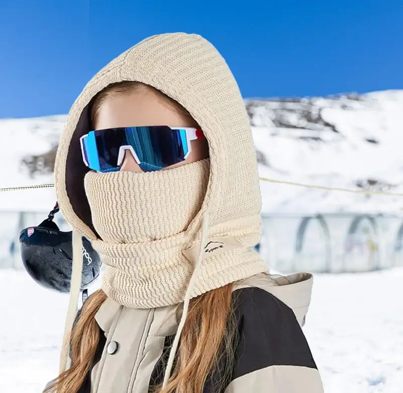 Cagoule Enfant Hiver beige avec tour de cou, portée par une fille dans un environnement enneigé. Design pratique pour protéger la tête et le cou contre le froid intense.