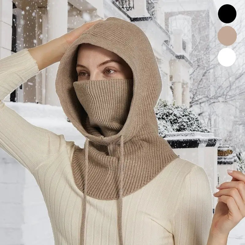 Femme portant une cagoule beige avec tour de cou intégré en tricot épais, ajustable avec des cordons, dans un décor enneigé. Parfait pour les activités hivernales.