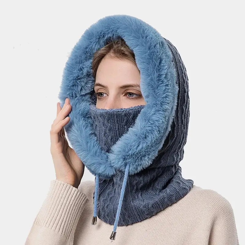 Femme portant une cagoule bleue élégante en tricot avec doublure épaisse en fourrure, capuche ajustable pour une protection optimale contre le froid hivernal.