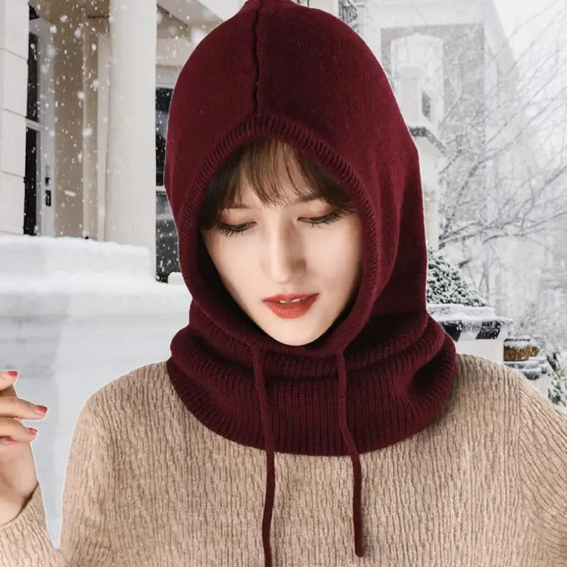 Femme portant une cagoule femme hiver en pleine rue enneigée. Son design en tricot et sa doublure douce garantissent chaleur et confort par temps froid.