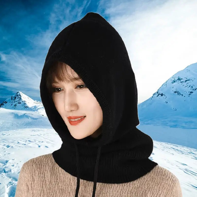 Femme portant une cagoule femme hiver noire sur un fond enneigé, idéale pour le ski et les activités outdoor, offrant une protection complète contre le froid.