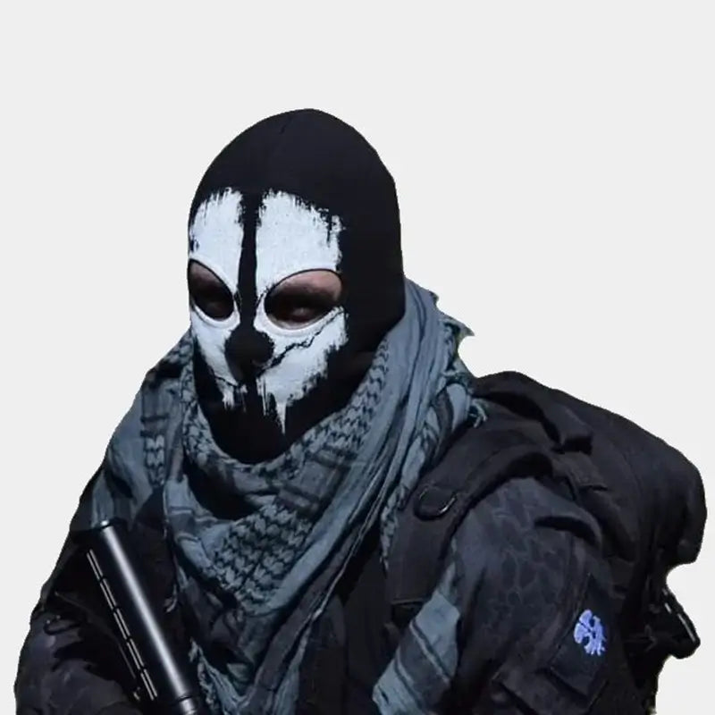 Cagoule-ghost noire avec motif de crâne blanc inspiré du personnage Ghost, portée par une personne équipée d'un foulard tactique et d'un sac à dos, idéale pour les activités comme l'airsoft ou les déguisements.