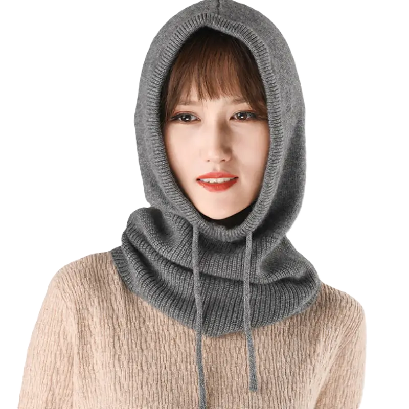 Femme portant une cagoule hiver femme en tricot gris foncé avec cordons ajustables, couvrant la tête et le cou, sur fond noir pour un contraste élégant.