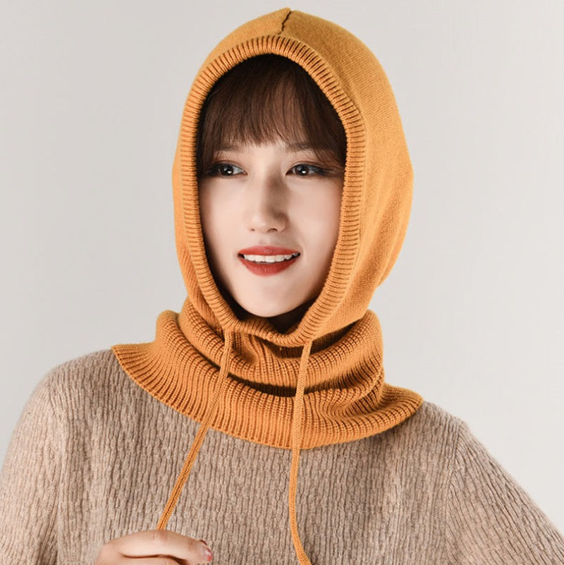 Femme souriante portant une cagoule laine Femme orange, tricotée avec des cordons ajustables, offrant une protection élégante et chaude pour l'hiver.