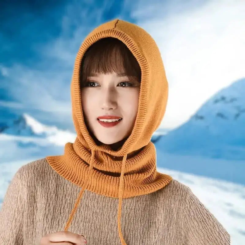 Femme souriante portant une cagoule laine Femme orange dans un environnement enneigé, idéale pour les activités hivernales