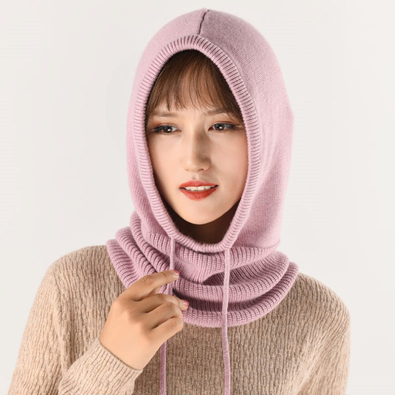 Femme souriante portant une cagoule laine Femme rose, tricotée avec des cordons ajustables, offrant une protection élégante et chaude pour l'hiver.