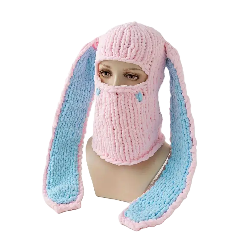 Cagoule Oreilles de lapin rose et bleue sur mannequin – Un bonnet cagoule en laine rose avec de longues oreilles de lapin en fausse fourrure bleue. Un accessoire mignon et chaud pour l’hiver.