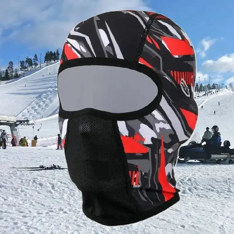 Cagoule pour Casque ski rouge à motifs, portée sur une piste enneigée en station de ski, protégeant le visage du froid.