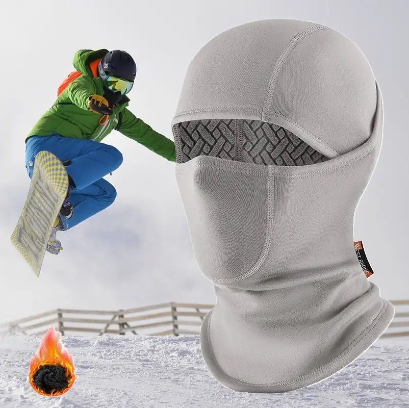 Cagoule ski doublure jacquard grise, conçue pour protéger du froid avec une isolation thermique renforcée, présentée sur un fond enneigé avec un snowboarder en action, illustrant sa performance dans des environnements extrêmes.