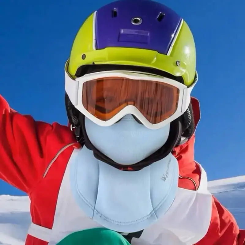 Enfant portant une cagoule de ski enfant bleue clair sous un casque jaune, idéal pour les activités hivernales en extérieur.