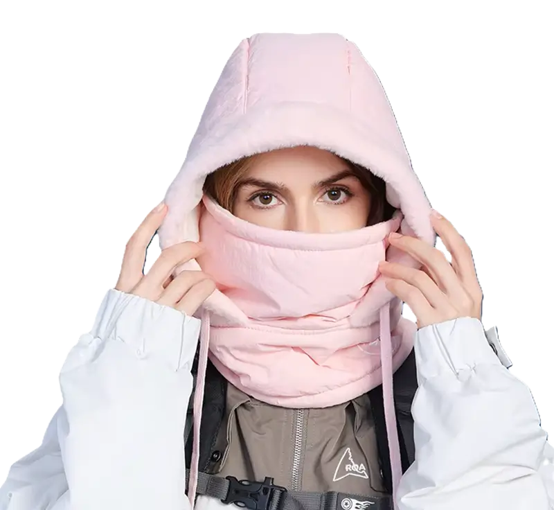 Femme portant une cagoule ski femme waterproof rose, tenant sa capuche ajustable, idéale pour protéger du froid et de l'humidité lors des activités de ski ou d'extérieur en hiver.