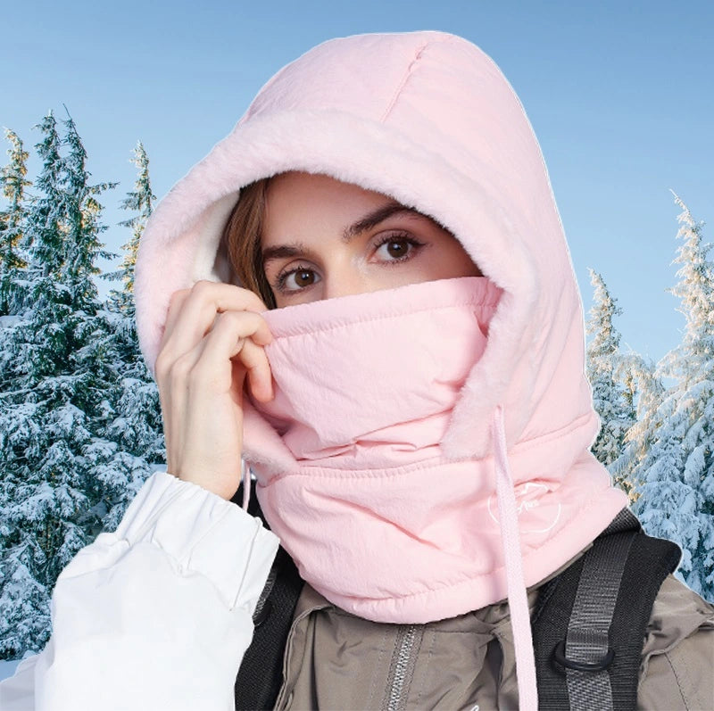 Femme portant une cagoule ski femme waterproof rose, parfaitement ajustée pour l'hiver, avec un paysage enneigé en arrière-plan, offrant une protection contre le froid et l'humidité.