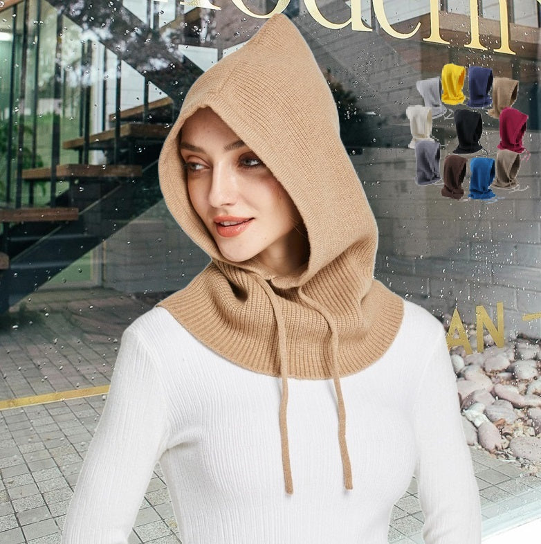 Cagoule Tricot Femme beige portée par une femme avec un pull blanc, dans un décor extérieur moderne avec des escaliers en arrière-plan. Plusieurs couleurs de cagoules sont visibles en miniature dans le coin supérieur droit.