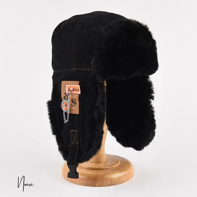 Chapka femme hiver noire avec fourrure assortie, dotée d'une étiquette en cuir et d'attaches pratiques, idéale pour l'hiver.