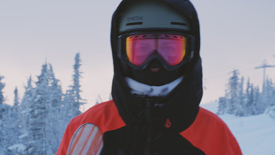 Homme avec cagoule et tenue de ski complète se dirigeant vers le sommet des montagnes pour skier 